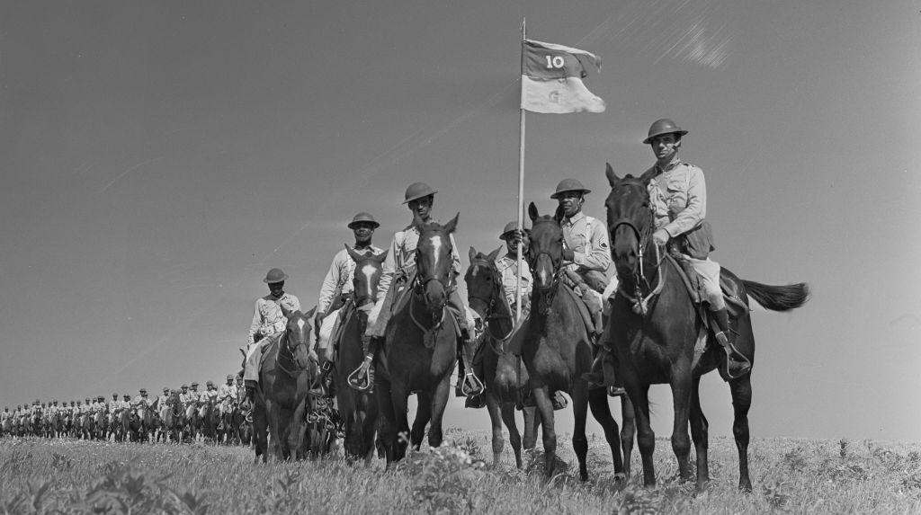 Mounted soldiers of the 10th U.S. Cavalry on horseback, carrying a guidon marked 10